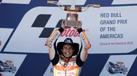 Pembalap Repsol Honda, Marc Marquez mengangkat trofi juara MotoGP Amerika di Circuit of the Americas (COTA), Austin, Minggu (22/4). Sebelum lomba, Marquez kena hukuman mundur tiga posisi karena melakukan pelanggaran di sesi kualifikasi. (AP/Eric Gay)