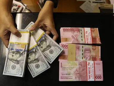 Pekerja menunjukan mata uang Rupiah dan Dolar AS di Jakarta, Rabu (19/6/2019). Nilai tukar rupiah terhadap dolar Amerika Serikat (AS) sore ini Rabu (19/6) ditutup menguat sebesar Rp 14.269 per dolar AS atau menguat 56,0 poin (0,39 persen) dari penutupan sebelumnya. (Liputan6.com/Angga Yuniar )