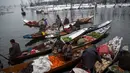 Pedagang menjual sayur dan buah-buahan di pasar terapung di danau Dal, Srinagar, Kashmir India, (25/1). Dinginnya salju para pedagang ini tetap bersemangat menjajakan dagangannya di atas perahu. (AP Photo/Dar Yasin)