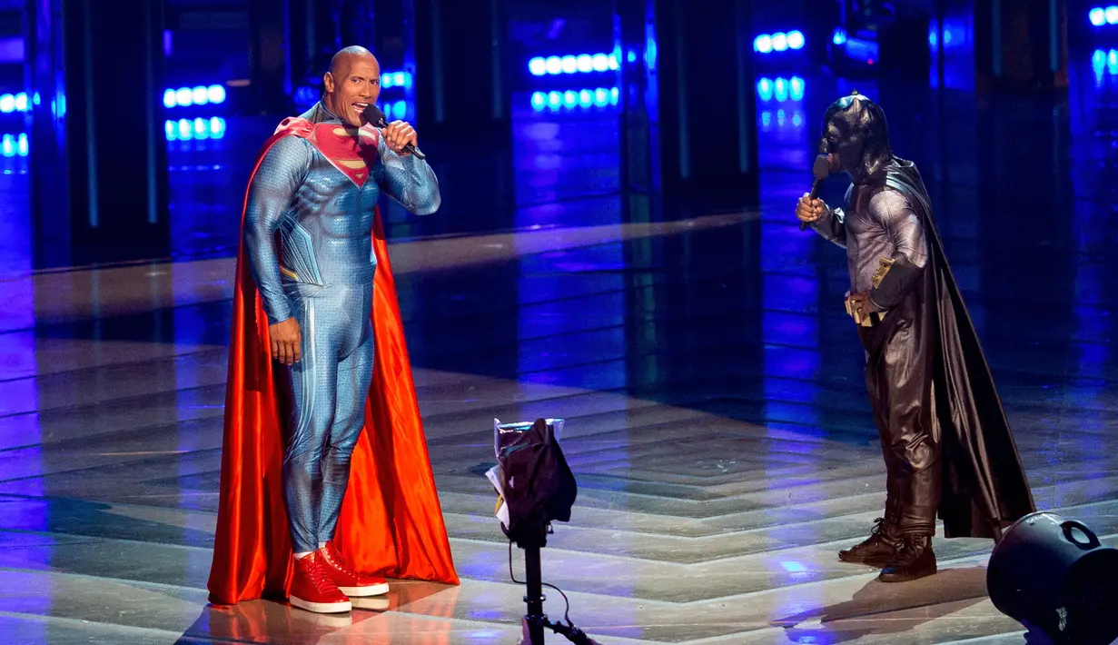 Aktor Dwayne Johnson (kiri) dan Kevin Hart menjadi pembawa acara MTV Movie Awards 2016  di Warner Bros Studios, California, (9/4). Uniknya Dwayne dan kevin mengenakan kostum Superman dan Batman saat membawakan acara tersebut. (CHRISTOPHER POLK/AFP)   