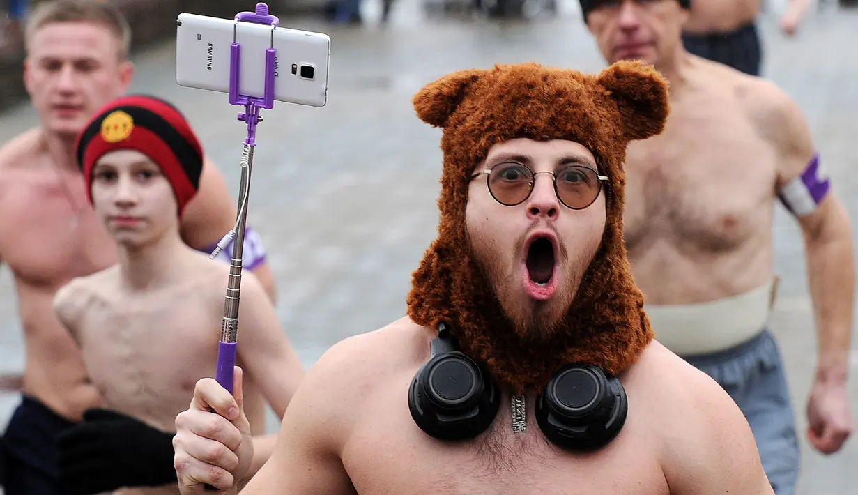 Seorang pria menggunakan topi sambil membawa tongkat selfie saat berpartisipasi dalam acara "Real men's race" di Minsk, Belarusia, Kamis (23/2). Meski cuaca cukup dingin, lomba lari ini mampu menarik partisipasi ratusan peserta. (Sergei GAPON/AFP)