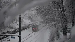 Sebuah kereta melaju di tengah salju di Milan, Italia (28/12/2020). Sekitar 20 sentimeter salju turun di kota itu, di mana seorang pria tunawisma berusia 76 tahun meninggal di rumah sakit setelah ditemukan di jalan. (Xinhua/Daniele Mascolo)