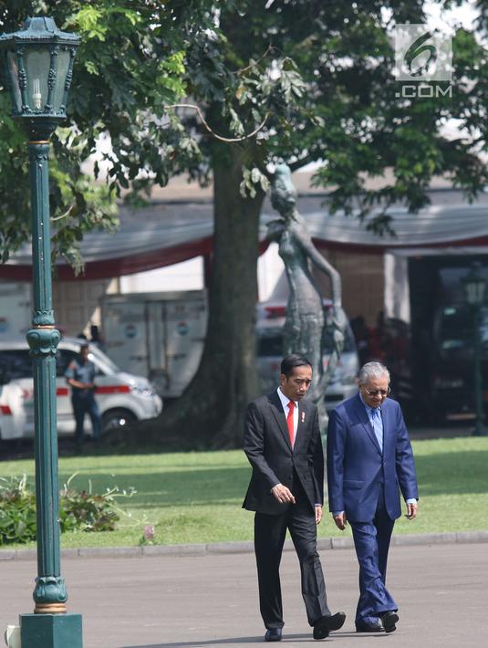 Presiden Joko Widodo (Jokowi) berjalan bersama PM Malaysia, Mahathir Mohamad usai menaman pohon di halaman belakang Istana Bogor, Jumat (29/6). Sebelum kegiatan menanam pohon, PM Malaysia disambut dengan upacara kenegaraan. (Liputan6.com/Angga Yuniar)