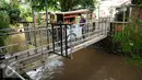 Pedagang menyebrang di jembatan Kali Krukut, Kemang, Jakarta (29/9). Pemprov DKI berencana untuk menormalisasi Kali Krukut. (Liputan6.com/Gempur M Surya) 