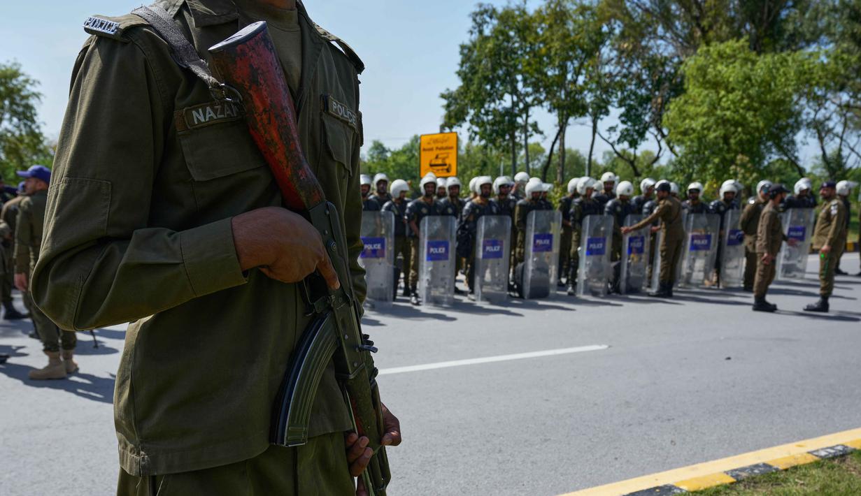 Pertemuan ini menyusul kesepakatan gencatan senjata sementara selama dua minggu di tengah ketegangan tinggi antara Iran dan Amerika Serikat dengan fokus utama pada keamanan di Selat Hormuz. Tampak dalam foto, seorang petugas polisi berjaga sementara yang lain mengikuti pengarahan sebelum penugasan mereka di Islamabad, Pakistan, untuk memastikan keamanan menjelang kemungkinan negosiasi antara Iran dan Amerika Serikat, Jumat 10 April 2026. (AP Photo/Anjum Naveed)