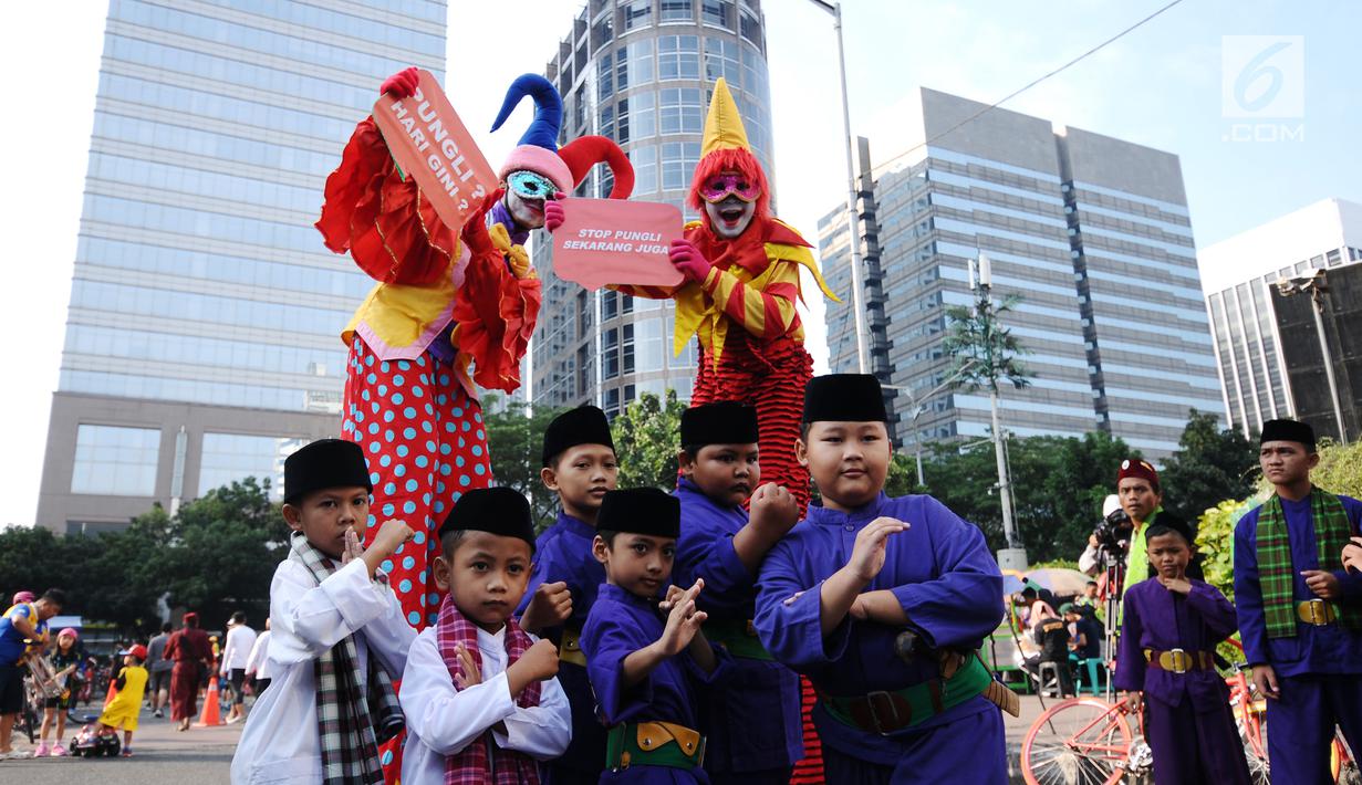 Pesilat cilik bersama badut berpose saat social community gathering Satgas Saber Pungli di Jakarta, Minggu (17/9). Kemenko Polhukam meluncurkan maskot dan melakukan sosialisasi satgas saber pungli. (Liputan6.com/Helmi Fithriansyah) 