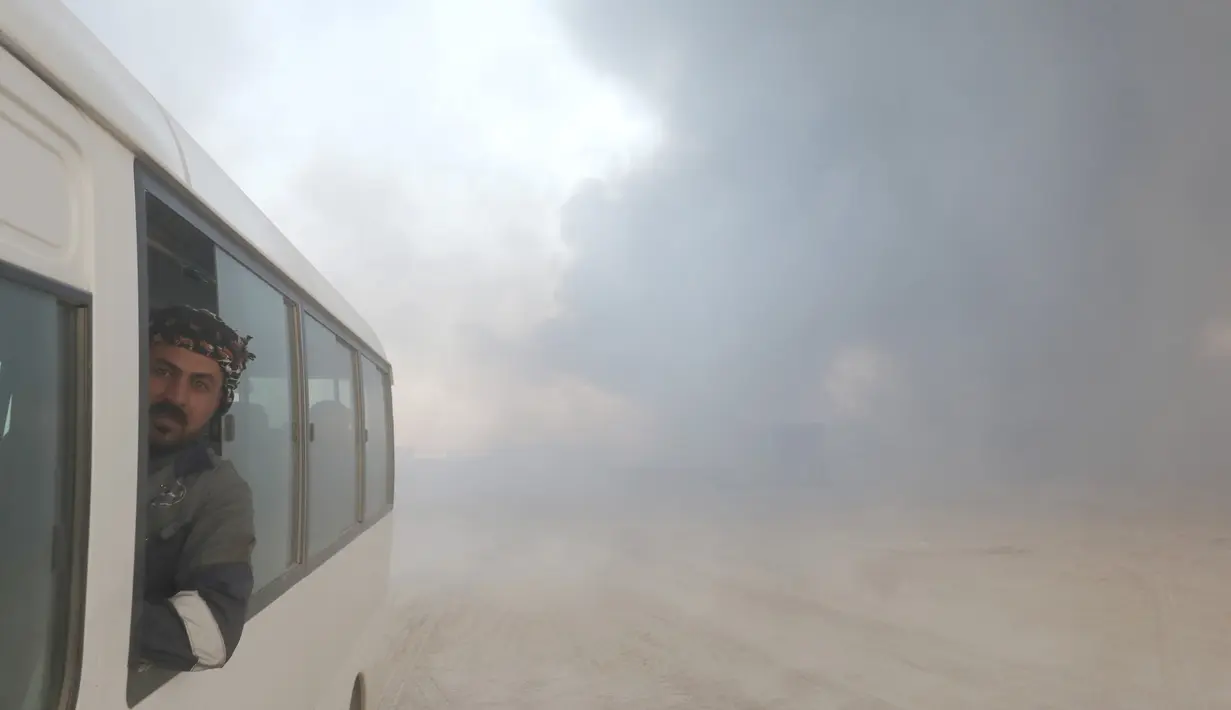 Seorang pekerja tambang minyak berada di dalam bus setelah ladang minyak dibakar oleh ISIS di Qayyara, selatan Mosul, Irak, (23/11). Sebelumnya, sekitar enam sumur minyak telah dibakar ISIS di kawasan tersebut. (REUTERS/Goran Tomasevic)