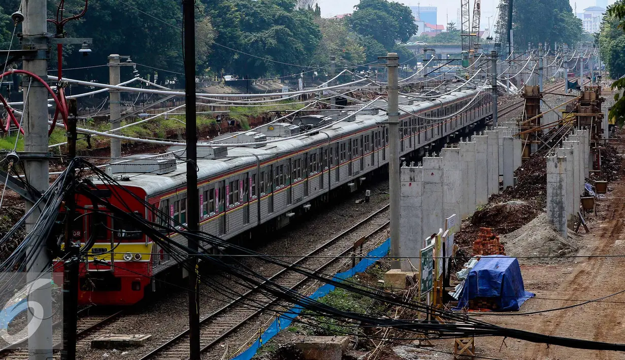 Sebuah Kereta Rel Listrik (KRL) melaju di samping lokasi pembangunan Stasiun Sudirman Baru di Jakarta, Rabu (9/11). Stasiun itu hanya melayani penumpang dari dan menuju bandara, yang nantinya terintegrasi dengan Stasiun MRT. (Liputan6.com/Faizal Fanani)