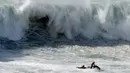 Peselancar ditarik menggunakan jet ski setelah jatuh ketika unjuk kebolehan dalam menaklukkan ombak besar di Praia do Norte atau Pantai Utara, Nazare, Portugal, Rabu (20/11/2019). Hanya peselancar profesional yang boleh bermain ombak di perairan ini. (AP Photo/Armando Franca)