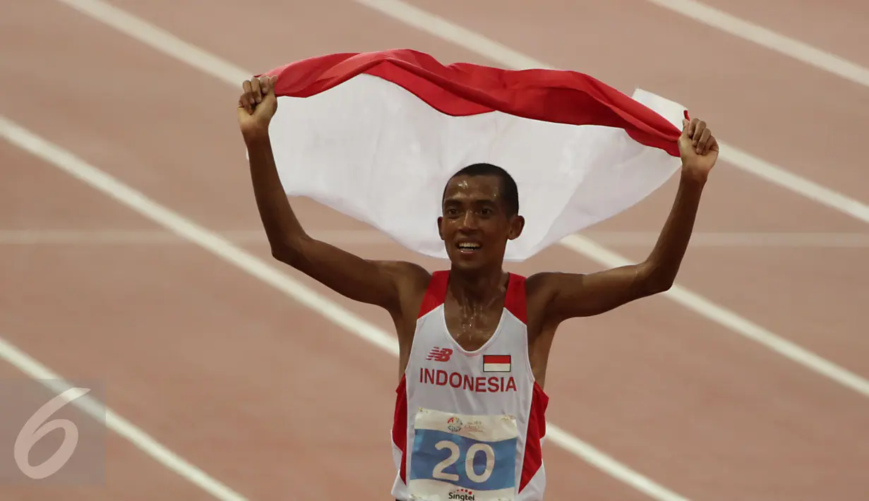 Pelari Indonesia, Agus Prayogo melakukan victory lap sambil mengibarkan sang Merah Putih saat merayakan kemenangannya di nomor lari 10.000 m putra SEA Games 2015 di National Stadium, Singapura, Rabu (10/6/2015). (Liputan6.com/Helmi Fithriansyah)