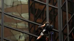 Sejumlah petugas NYPD menunggu seorang pria yang memanjat gedung Trump Tower sebelum bersiap-siap menahannya di New York, AS, Rabu (10/8). Petugas berhasil menangkap si pria berambut gondrong itu ketika mencapai lantai 21. (REUTERS/Lucas Jackson)