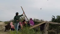 Sejumlah warga saat santai sembari menyaksikan helikopter waterboombing yang melakukan pemadaman di lokasi karhutla gambut di Dusun Puding, Kecamatan Kumpeh, Kabupaten Muarojambi, Kamis (3/10/2019). (Liputan6.com/Gresi Plasmanto)