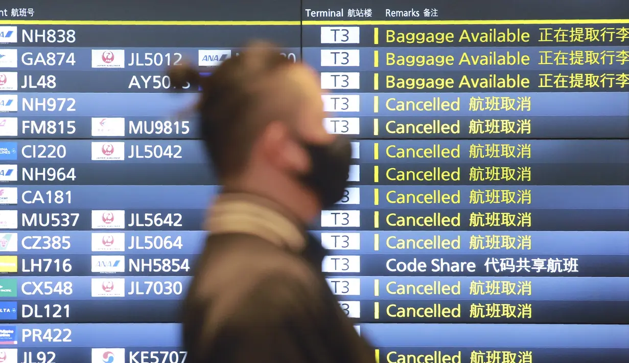Seorang pria melewati papan informasi penerbangan di Bandara Internasional Haneda di Tokyo, Senin (28/12/2020). Jepang untuk sementara waktu melarang semua pendatang asing yang bukan penduduk masuk sebagai bentuk antisipasi varian baru COVID-19 hingga akhir Januari 2021. (AP Photo/Koji Sasahara)