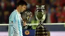 Lionel Messi, diantara trofi juara Copa America yang kembali gagal diraihnya. (AFP PHOTO/RODRIGO ARANGUA)