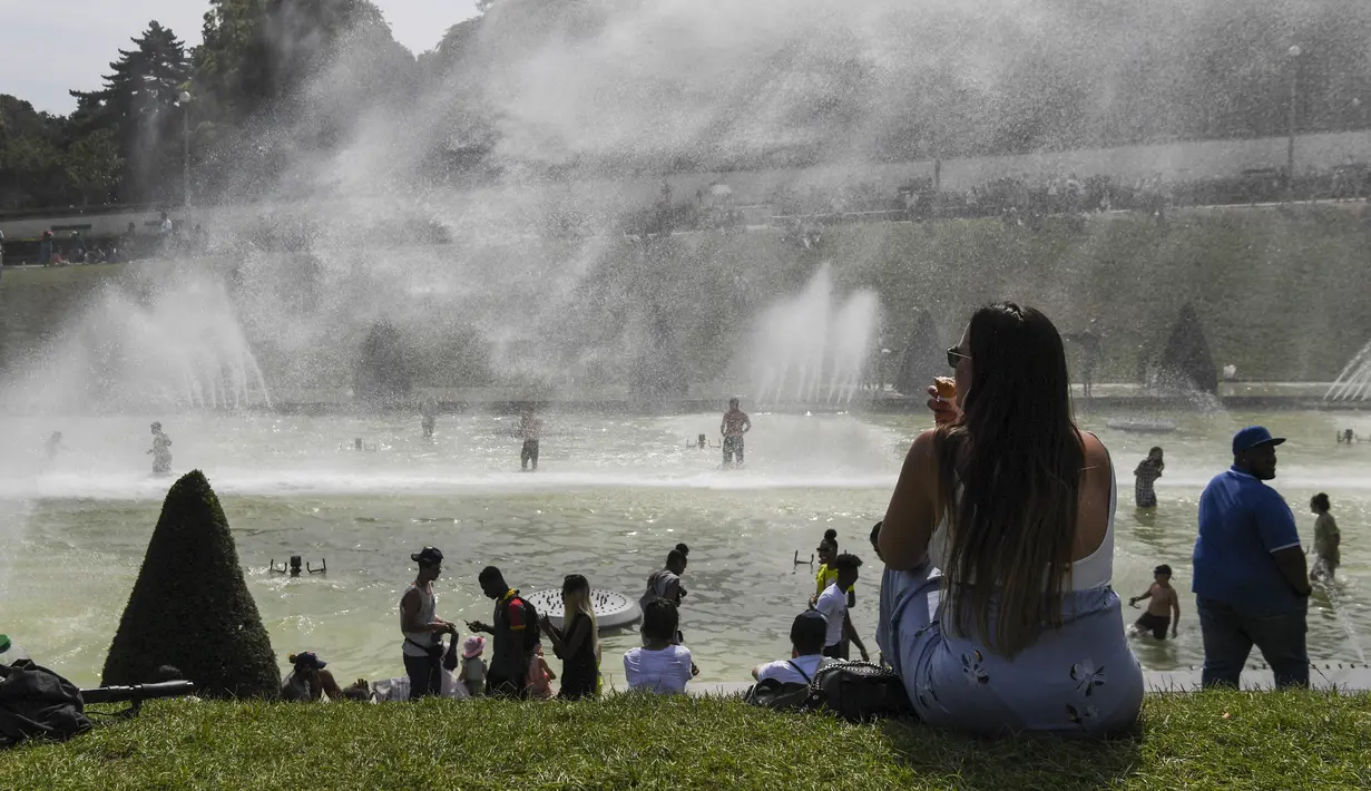 Sejumlah warga bermain di kolam air mancur di Trocadero Fountains dekat Menara Eiffel, Paris (22/7/2019). Warga Paris bersiap menghadapi suhu terpanas pada minggu ini ketika gelombang panas akan melanda ke Eropa utara. (AFP Photo/Alain Jocard)
