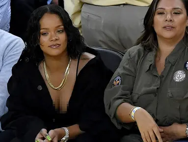 Penyanyi Rihanna saat menyaksikan pertandingan gim pertama Final NBA 2017 antara Golden State Warriors melawan Cleveland Cavaliers di Oracle Arena, Oakland, (1/6). Rihanna tampil dengan busana berwara hitam. (Thearon W. Henderson/Getty Images/AFP)