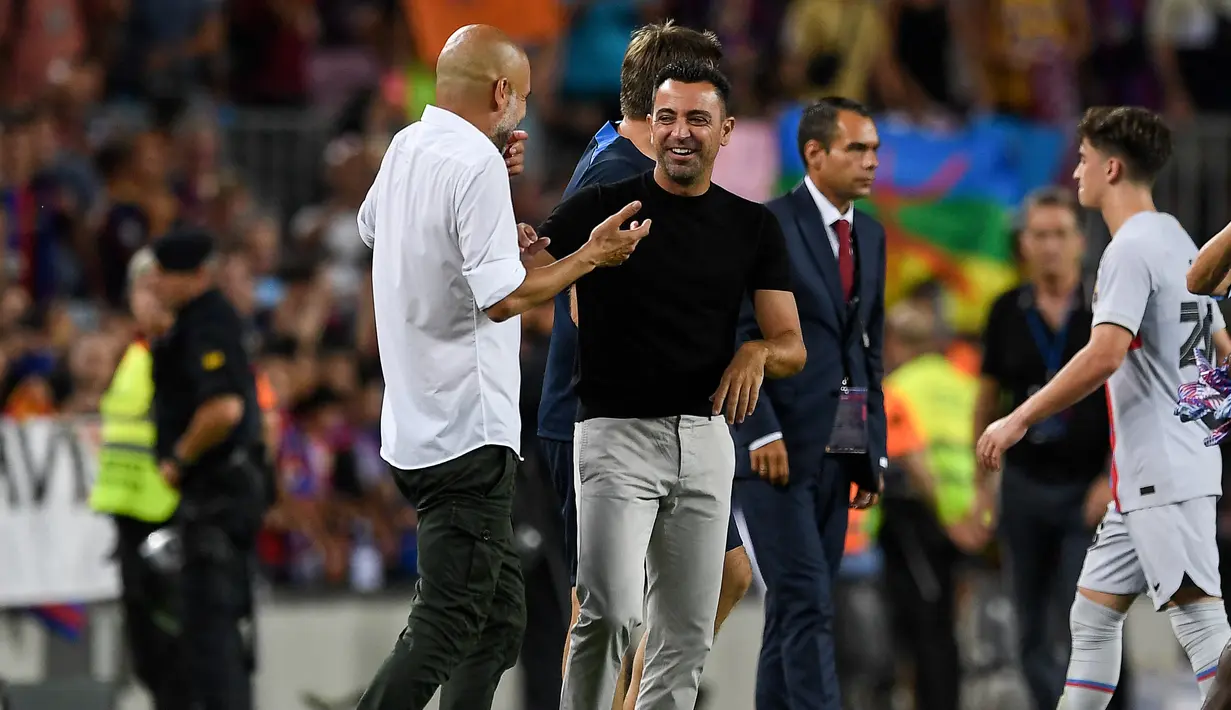 Manajer Manchester City, Pep Guardiola (kiri) berbincang dengan pelatih Barcelona Xavi Hernandez pada akhir sebuah laga amal di Stadion Camp Nou, Kamis (25/8/2022) dinihari WIB. Laga ini berlangsung menarik karena mempertemukan sang guru dan murid yaitu Pep Guardiola selaku pelatih Man City dan Xavi Hernandes pelatih Barcelona. (Photo by Josep LAGO / AFP)