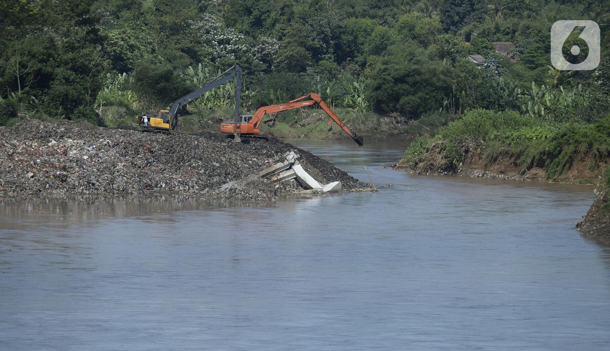 Pekerja menggunakan alat berat mengeruk sampah yang longsor di TPA Cipeucang, Serpong, Tangerang Selatan, Banten, Sebtu (23/5/2020). Turap penahan sampah TPA Cipeucang longsor pada 22 Mei 2020 dan hampir menutupi aliran Sungai Cisadane yang berada di sebelahnya. (merdeka.com/Dwi Narwoko