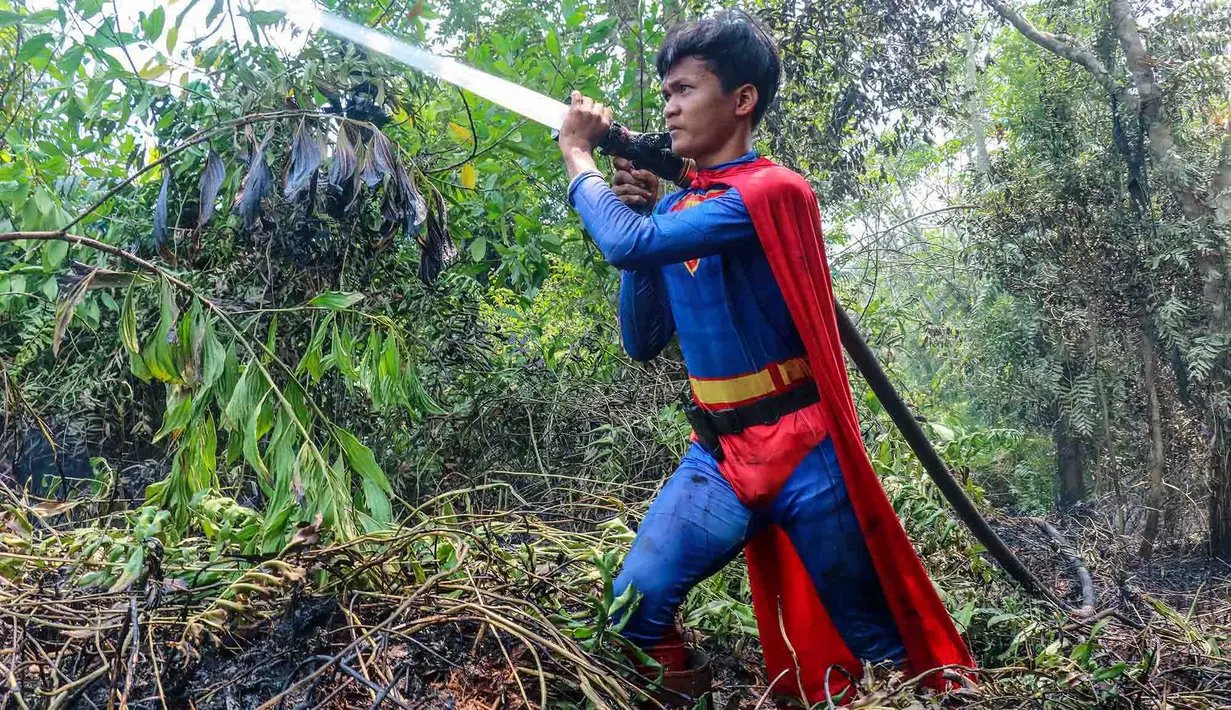 Pelajar bernama Rudiansyah dengan mengenakan kostum Superman membantu memadamkan kebakaran hutan dan lahan di Petuk Katimpun, Palangkaraya, Kalimantan Tengah, 17 Agustus 2026. (AFP/ Reina)