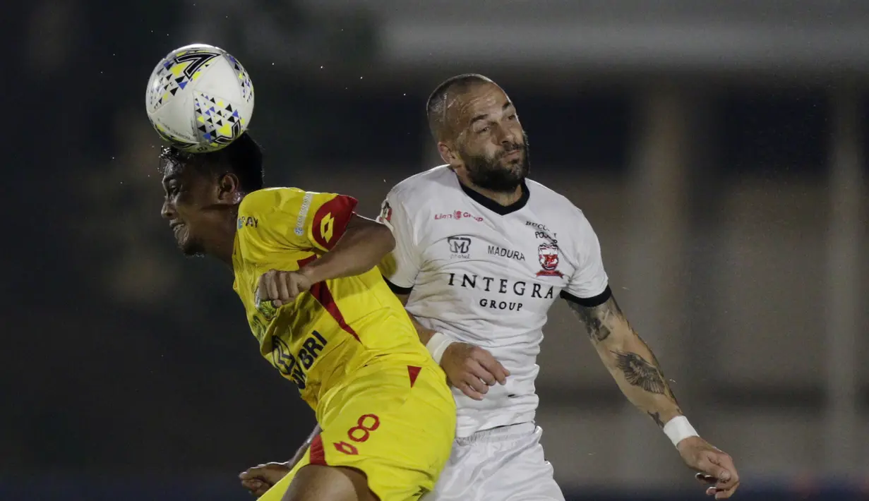 Gelandang Bhayangkara FC, M Hargianto, duel udara dengan striker Madura United, Aleksandar Rakic, pada laga Liga 1 2019 di Stadion Madya, Jakarta, Senin (5/8). (Bola.com/M iqbal Ichsan)