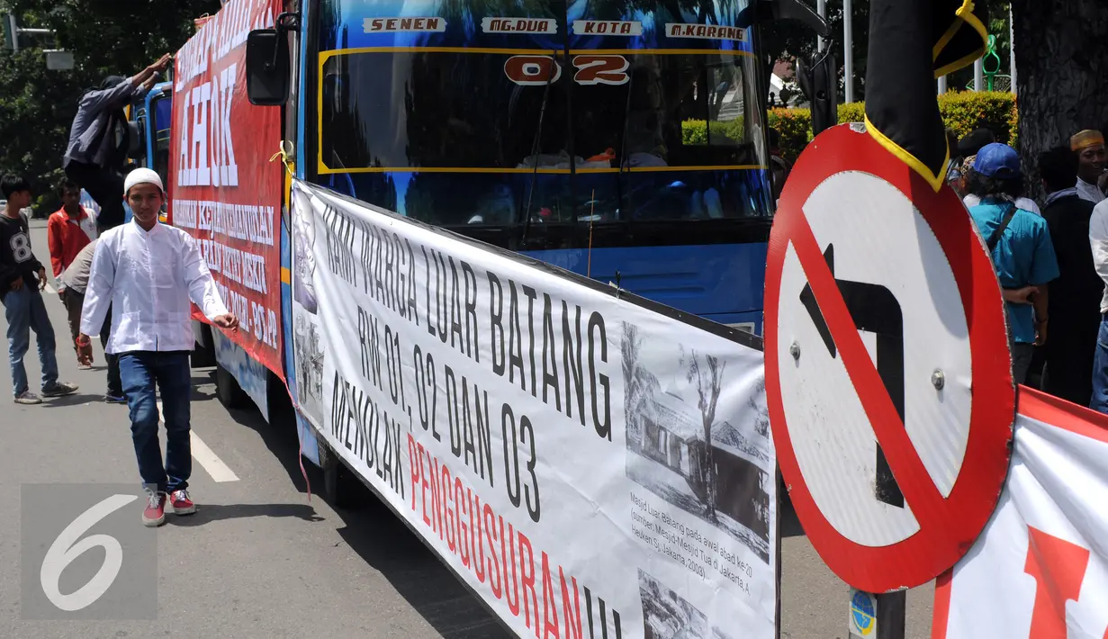 Seorang pemuda kampung Luar Batang melintas di depan spanduk tulisan saat melakukan aksi di depan Balai Kota Jakarta, Jumat (22/4/2016). Mereka mempertanyakan kebijakan Pemprov DKI Jakarta yang melakukan penggusuran. (Liputan6.com/Helmi Fithriansyah)