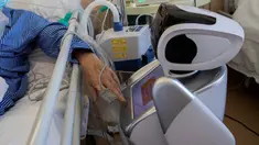 Pasien positif virus corona berinteraksi dengan robot di rumah sakit 'Ospedale di Circolo', di Varese, Italia pada 8 April 2020. Sebanyak enam unit robot yang tampak seperti manusia dan berjalan di atas roda ini membantu kinerja staf medis dalam merawat pasien virus corona Covid-19. (AP/Luca Bruno)