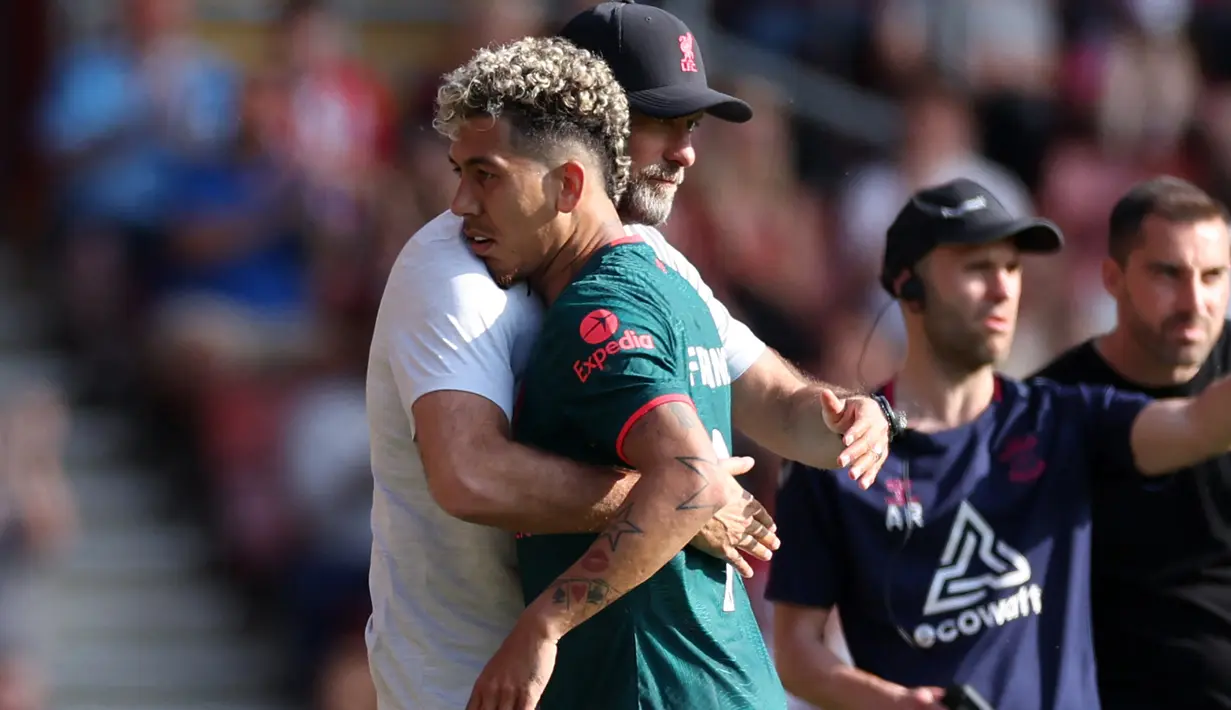 Pelatih Liverpool, Jurgen Klopp memeluk Roberto Firmino saat ditarik ke luar pada laga pekan terakhir Liga Inggris 2022/2023 menghadapi Southampton di St Mary's Stadium, Southampton, Minggu (28/5/2023) malam WIB. (AFP/Adrian Dennis)
