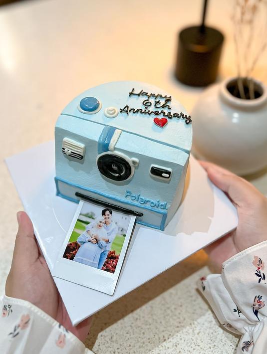 Detail kue anniversary Anisa Rahma dan Anandito. Banyak yang salah fokus, netizen bertanya-tanya di mana Anisa Rahma memesan kue tersebut. Kue anniversary tersebut didesain dengan warna biru agar selaras dengan foto romantis Anisa dan Anandito yang mengenakan busana warna biru. Detail tombol dan tulisan pada kue kamera polaroid ini juga unik. (Liputan6.com/IG/@anisarahma_12)