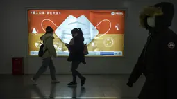 Para komuter yang mengenakan masker untuk melindungi diri dari COVID-19 berjalan melewati papan iklan yang mendorong warga untuk memakai masker di Beijing, China, Rabu (15/12/2021). China mendeteksi kasus kedua varian omicron pada seorang pria berusia 67 tahun. (AP Photo/Mark Schiefelbein)