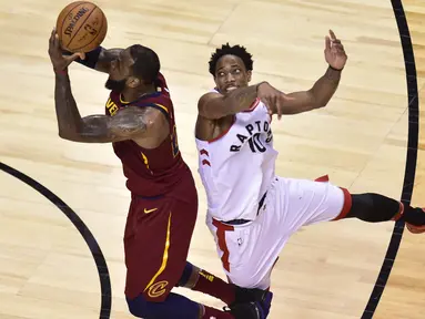 Pemain Cleveland, LeBron James (23) melakukan lay up saat diadang pemain Raptors, DeMar DeRozan (10) pada laga NBA playoffs Eastern Conference semifinal di Air Canada Centre, (1/2/2018). Cavaliers menang 113-112. (Frank Gunn/The Canadian Press via AP)