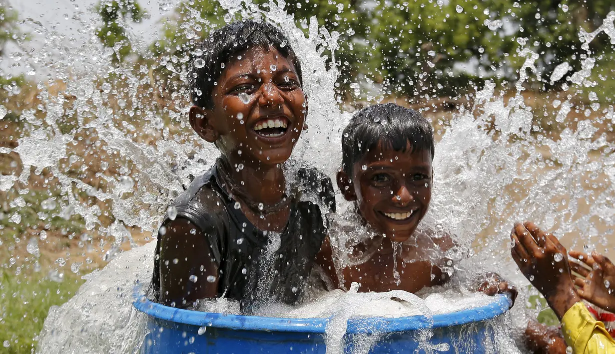 Dua anak berendam mendinginkan tubuhnya saat gelombang panas menerjang di pinggiran Ahmedabad, India, (28/5/2015). Gelombang panas di India telah menewaskan sedikitnya 1.371 karena suhu meningkat di atas 47 Celcius. (REUTERS/Amit Dave)