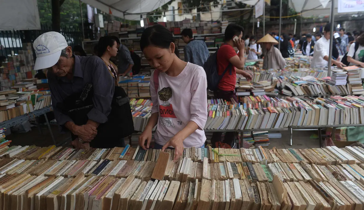 Seorang wanita mencari buku yang di dijual selama pameran buku bekas di Hanoi, Vietnam (26/10).( AFP Photo/Hoang Dinh Nam)