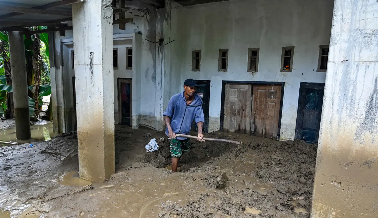 Salah satu wilayah yang mengalami dampak paling berat adalah Kabupaten Pidie Jaya, terutama kawasan yang berada di sepanjang aliran Sungai Meureudu. Tampak dalam foto, seorang warga membersihkan lumpur tebal dari pintu masuk rumahnya yang terendam banjir bandang di Meureudu, Kabupaten Pidie Jaya, Provinsi Aceh, Jumat 28 November 2025. (CHAIDEER MAHYUDDIN/AFP)
