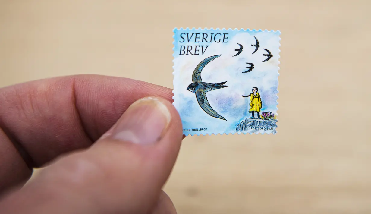 Seorang pria memegang prangko pos yang menggambarkan aktivis lingkungan remaja asal Swedia, Greta Thunberg di Stockholm pada 15 Januari 2021. Harga masing-masing prangko adalah 12 kronor atau sekitar 20 ribu rupiah. (Jonathan NACKSTRAND/AFP)