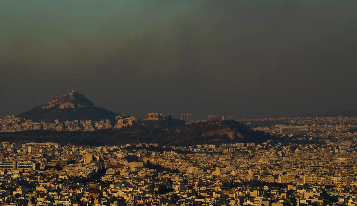 Pemandangan umum Athena dengan bukit Acropolis terlihat saat api membakar bagian utara kota pada hari Senin, 12 Agustus 2024. (AP Photo/Petros Giannakouris)
