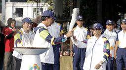 Gubernur DIY Sri Sultan Hamengku Buwono X memberikan api obor kepada Menlu RI, Retno Marsudi, di Pagelaran Keraton Yogyakarta, Kamis (19/7/2018). Total jarak kirab Obor di Yogya ini sepanjang 11,5 kilometer. (Bola.com/M Iqbal Ichsan)