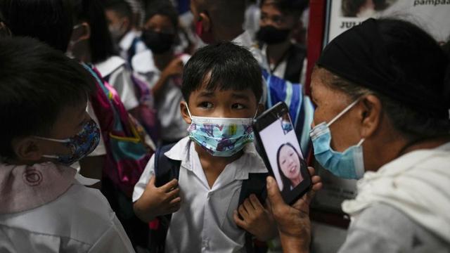 Seorang anak laki-laki berbicara dengan ibunya dari smartphone di Sekolah Dasar San Juan di metro Manila, Filipina pada Senin, 22 Agustus 2022.Ini pembukaan kelas tatap muka pertama setelah lockdown COVID-19. (Foto AP/Aaron Favila)