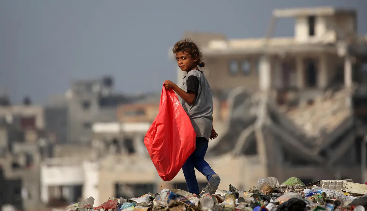 Seorang anak pengungsi Palestina membawa plastik besar untuk diisi dengan barang-barang yang ditemukan di tumpukan sampah, di kamp pengungsi al-Bureij di Jalur Gaza tengah pada 10 November 2024. (Eyad BABA/AFP)