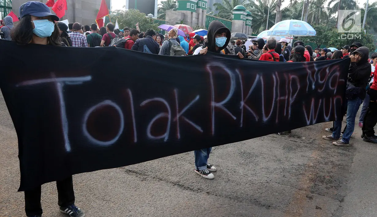 Massa membentangkan spanduk saat melakukan demontrasi di depan Gedung MPR/DPR, Jakarta, Senin (12/2). Mereka menolak KUHP dengan alasan KUHP tidak berpihak pada kelompok marjinal utamanya, Perempuan, Anak, ODHA, Minoritas, LGBT. (Liputan6.com/Johan Tallo)