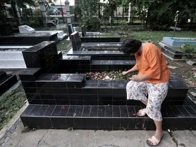 Keluarga membersihkan makam saat ziarah di kompleks pemakaman Gereja Tugu, Semper, Jakarta, Senin (23/12/2019). Ziarah menjadi tradisi keluarga keturunan Portugis di Kampung Tugu menjelang Hari Raya Natal. (merdeka.com/Iqbal Nugroho)