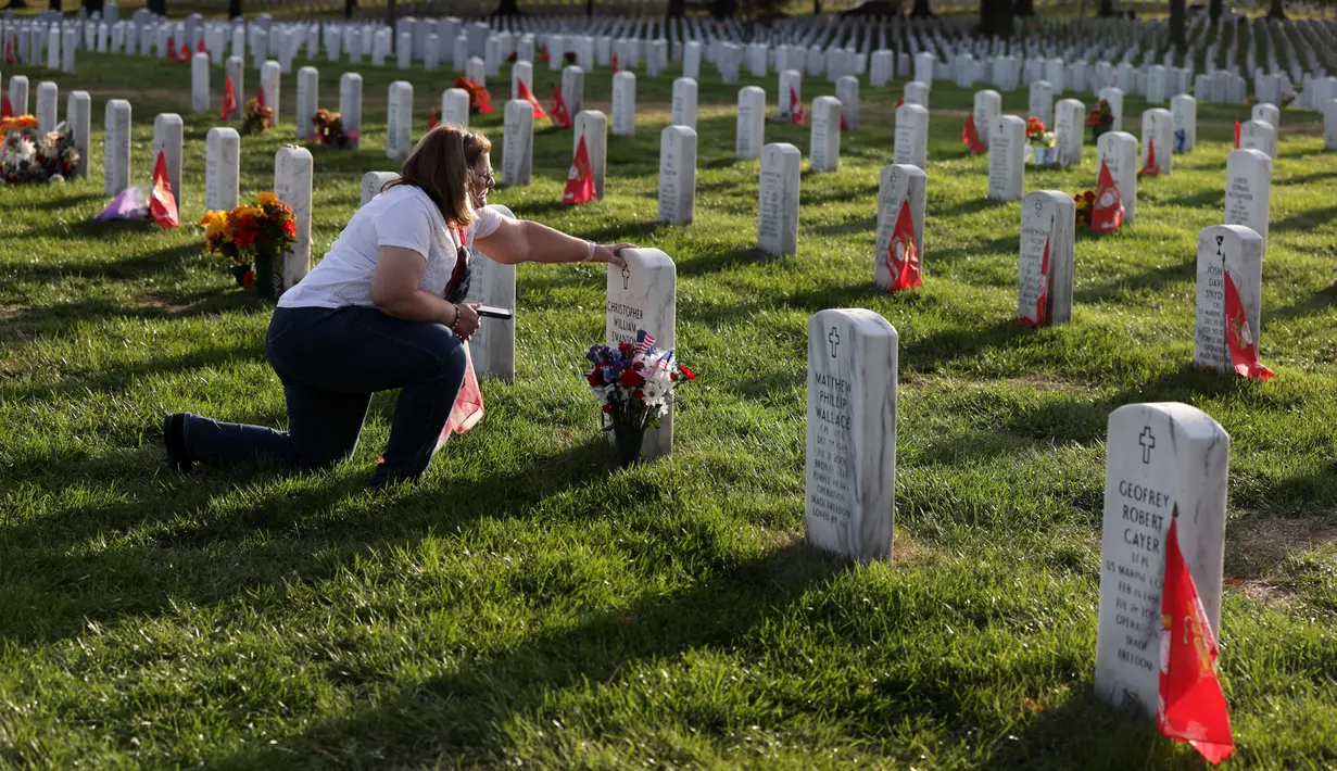 Kelly Swanson menyentuh batu nisan putranya Christopher William Swanson saat peringatan Hari Veteran, Arlington, Virginia, AS, Senin (11/11/2019). Rakyat AS memperingati Hari Veteran untuk menghormati mereka yang pernah bertugas di militer AS. (Alex Wong/Getty Images/AFP)