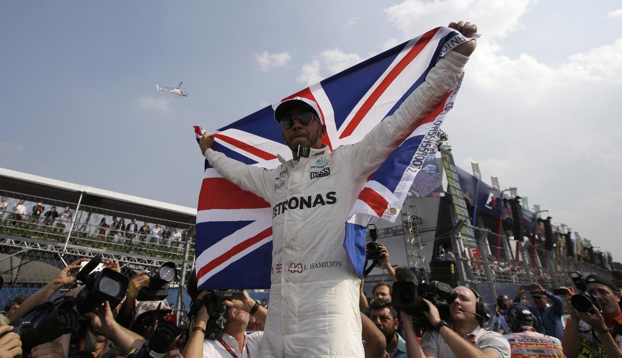 Gaya selebrasi Lewis Hamilton membentangkan bendera Inggris setelah memastikan diri meraih meraih gelar juara dunia F1 2017 di Hermanos Rodriguez racetrack, Mexico City, (29/10/20170). Hamilton finis kedelapan pada balapan tersebut. (AP/Moises Castillo)