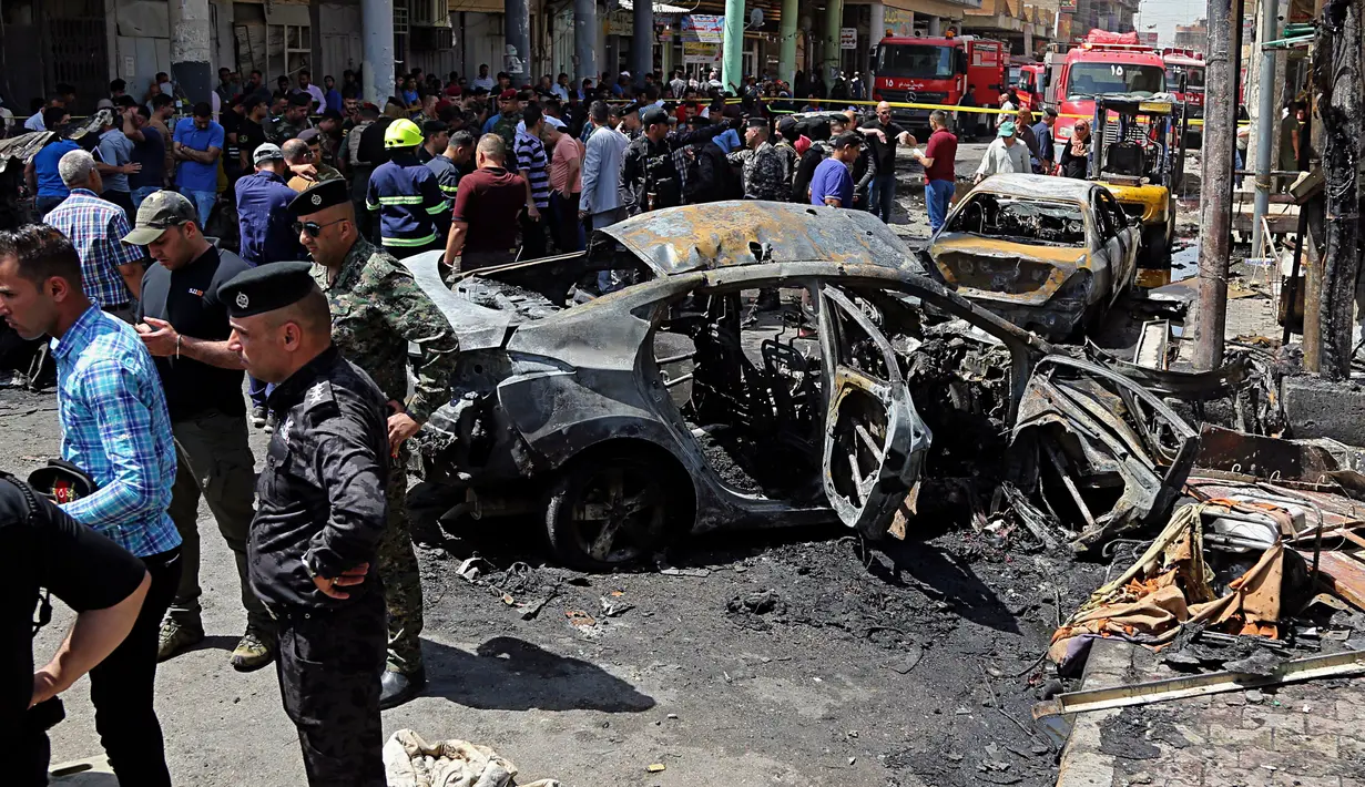 Pasukan keamanan Irak dan warga sipil memeriksa lokasi serangan bom di Baghdad, Irak (30/5). Lewat media propaganda Amaq, ISIS menyatakan bahwa pengebom bunuh diri tersebut menargetkan warga Syiah. (AP Photo / Karim Kadim)