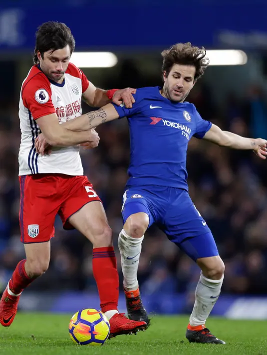 Pemain Chelsea, Cesc Fabregas berebut bola dengan pemain West Bromwich Albion, Claudio Yacob pada laga pekan ke-27 Premier League di Stamford Bridge, Selasa (13/2). Chelsea menang dengan tiga gol tanpa balas atas West Bromwich Albion. (AP/Alastair Grant)