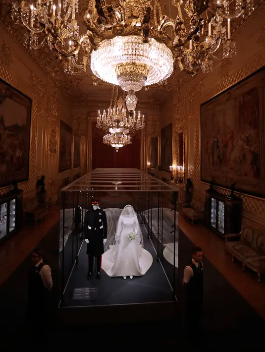 Petugas berjaga dekat gaun pernikahan Meghan Markle dan Pangeran Harry yang ditampilkan pada pameran “A Royal Wedding: The Duke and Duchess of Sussex” di Kastil Windsor, London, 25 Oktober 2018. Pameran ini dibuka hingga Januari 2019. (AP/Matt Dunham)