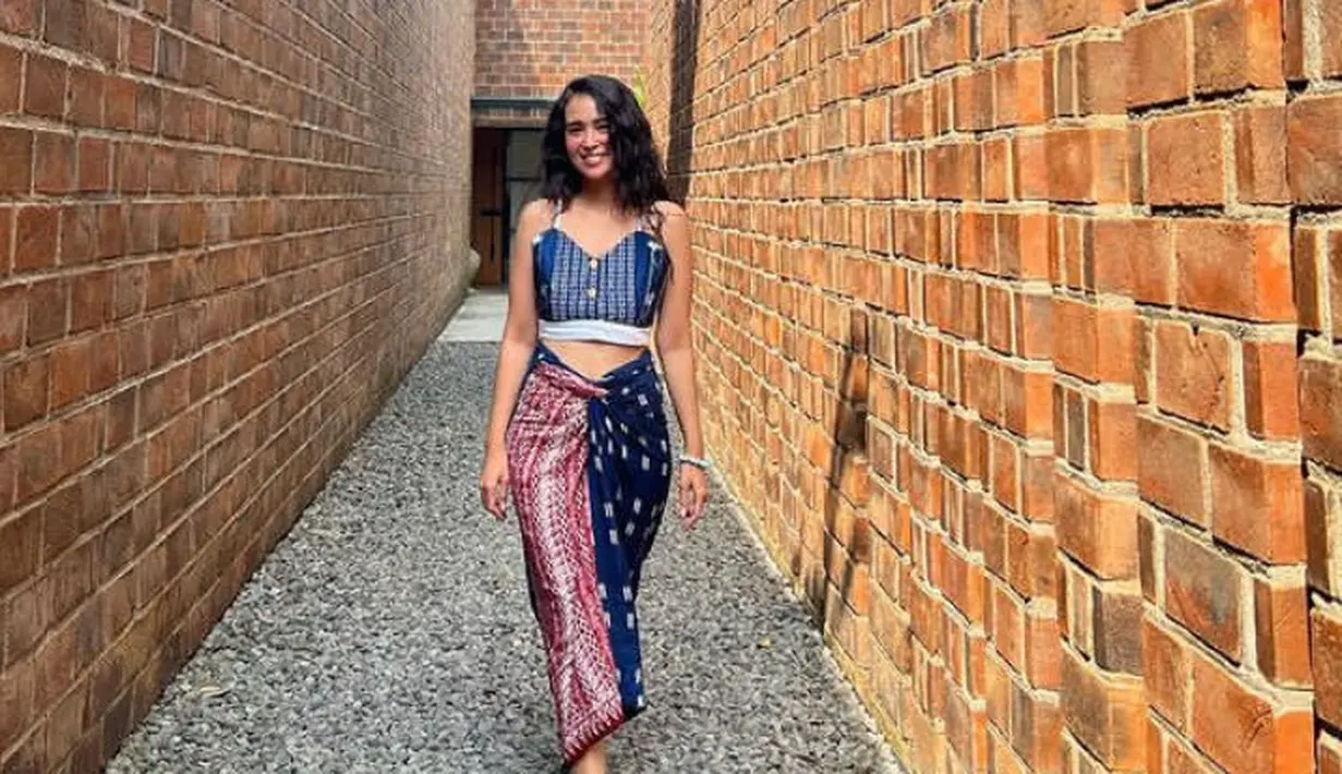 Ayushita tampil dengan atasan bercorak crop top spaghetti strap dipadukan kain lilit bermotif two tone, serta sandal hijaunya. [@ayushita]