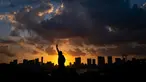 Replika Patung Liberty terlihat saat matahari terbenam di Odaiba, Tokyo, Jepang (29/7). Odaiba adalah sebuah pulau buatan di Teluk Tokyo, Jepang yang dihubungkan dengan pusat kota Tokyo dengan Jembatan Rainbow. (AFP Photo/Martin Bureau)