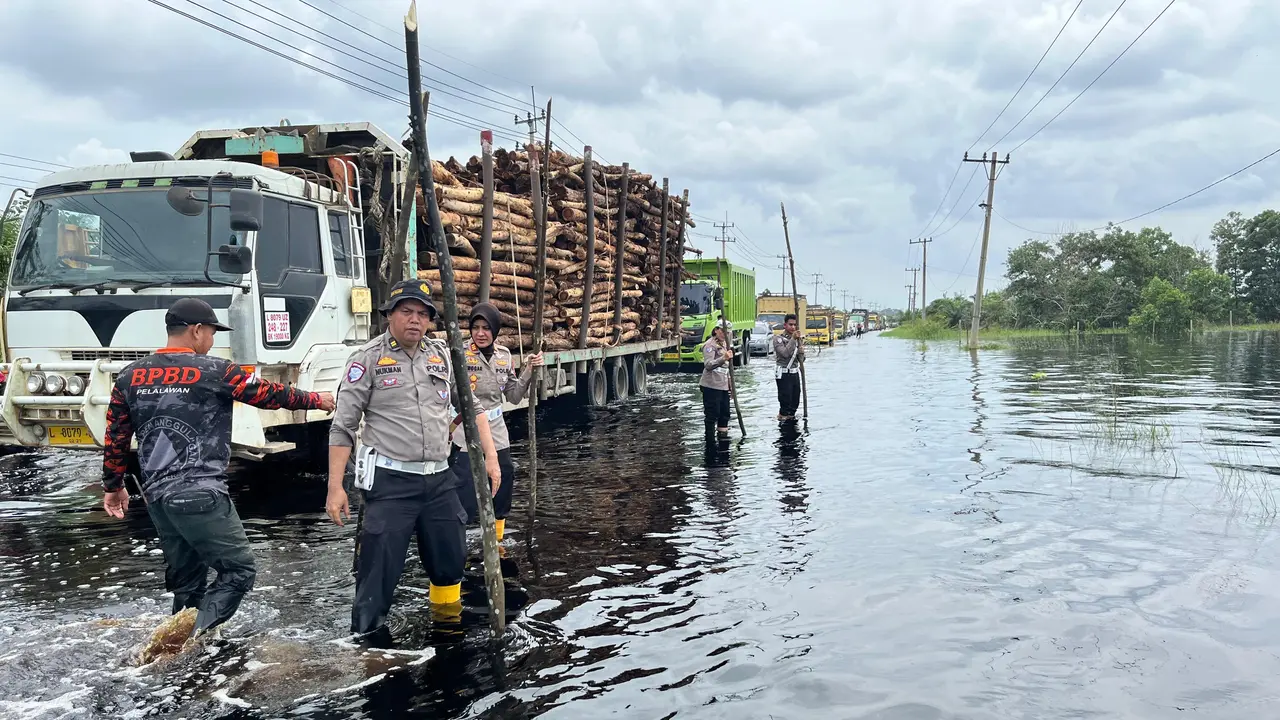 Polisi memasang tanda di Jalan Lintas Timur Sumatra yang terendam banjir agar kendaraan tidak terperosok ke lobang.