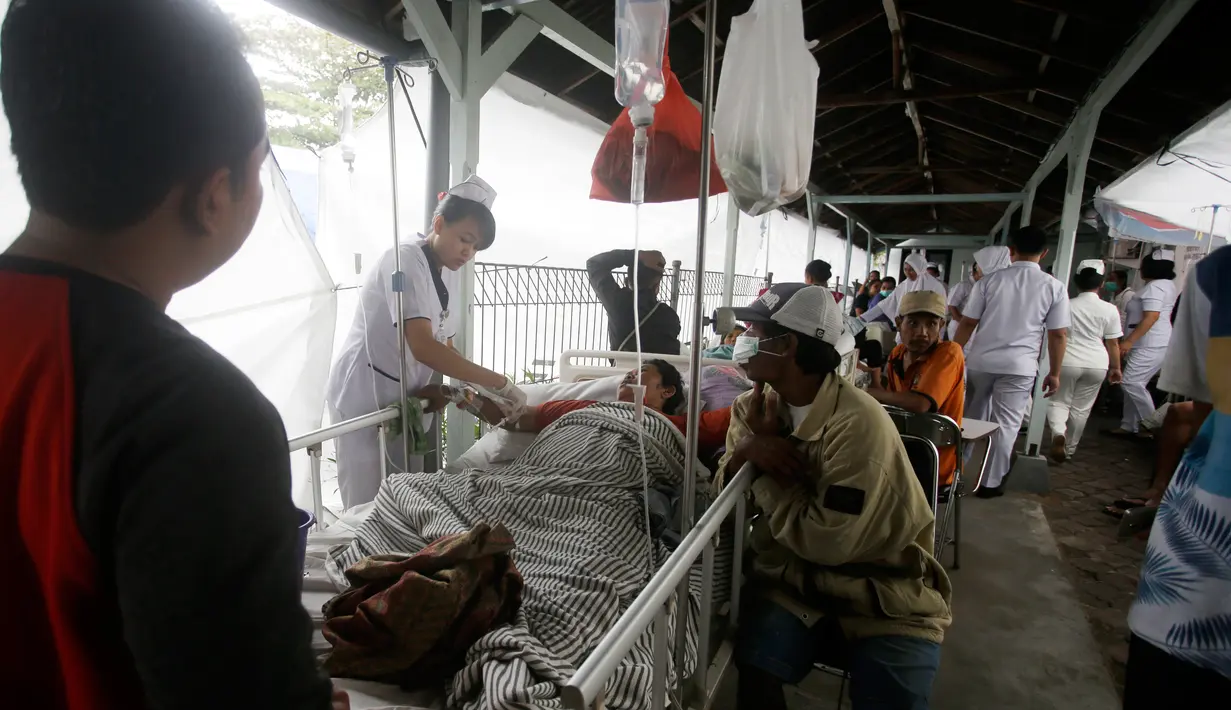 Pasien dievakuasi keluar rumah sakit di Bali menyusul gempa Lombok, Senin (6/8). Gempa 7 pada skala richter yang berpusat di Lombok, menyebabkan kerusakan bangunan di berbagai lokasi di Bali dan mengakibatkan sejumlah warga terluka. (AP/Firdia Lisnawati)