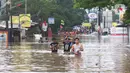 Warga melintasi banjir  yang merendam jalan Raya KH Hasyim Ashari, Ciledug ,Tangerang, Rabu (1/1/2020). Banjir setinggi dada orang dewasa membuat jalur penghubung Tangerang ke Jakarta tersebut terputus tidak dapat dilintasi. (Liputan6.com/Angga Yuniar)